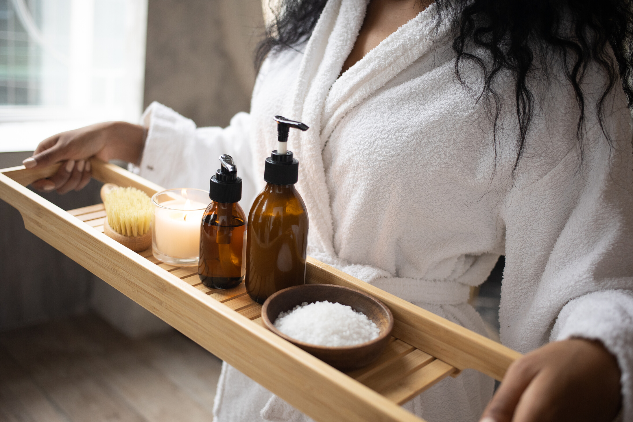Crop black woman with tray of spa products